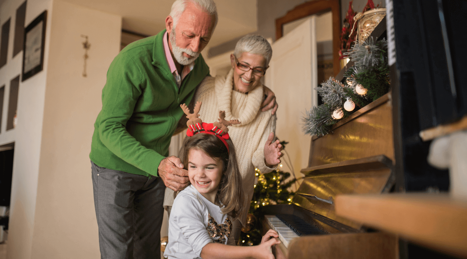 Child playing piano while her Grandparents stand behind her and enjoy the music