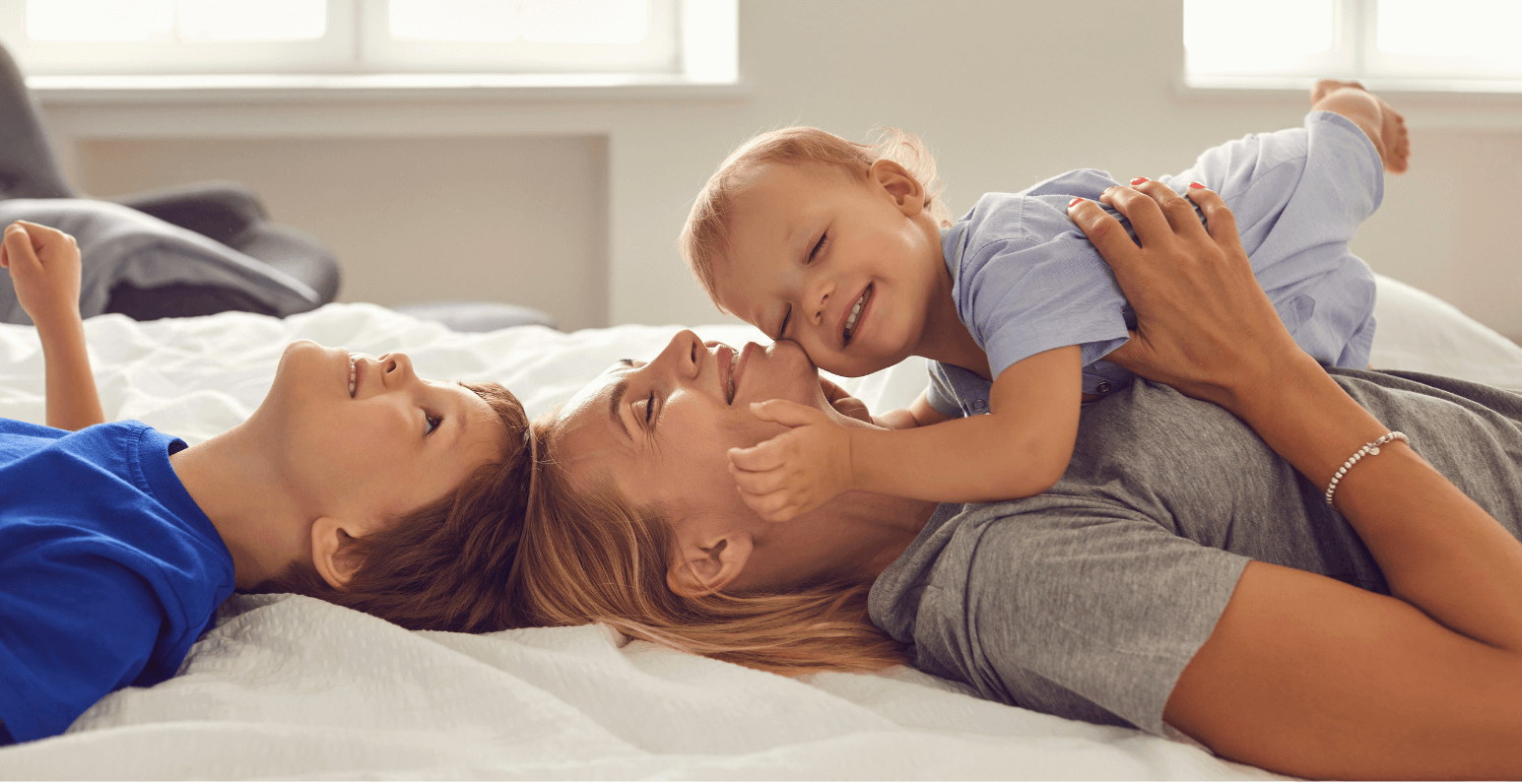 Baby laying on his mothers chest while holding her face and smiling