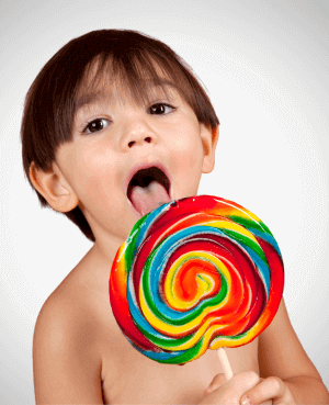 Child licking a large rainbow colored lollipop