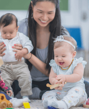 Childcare provider sitting with two babies