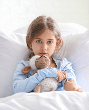 Sick child in bed holding a stuffed animal