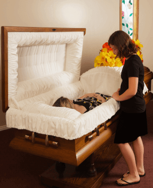 Mourning child standing next to an open casket
