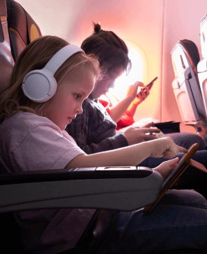 Children watching their tablets while sitting on an airplane