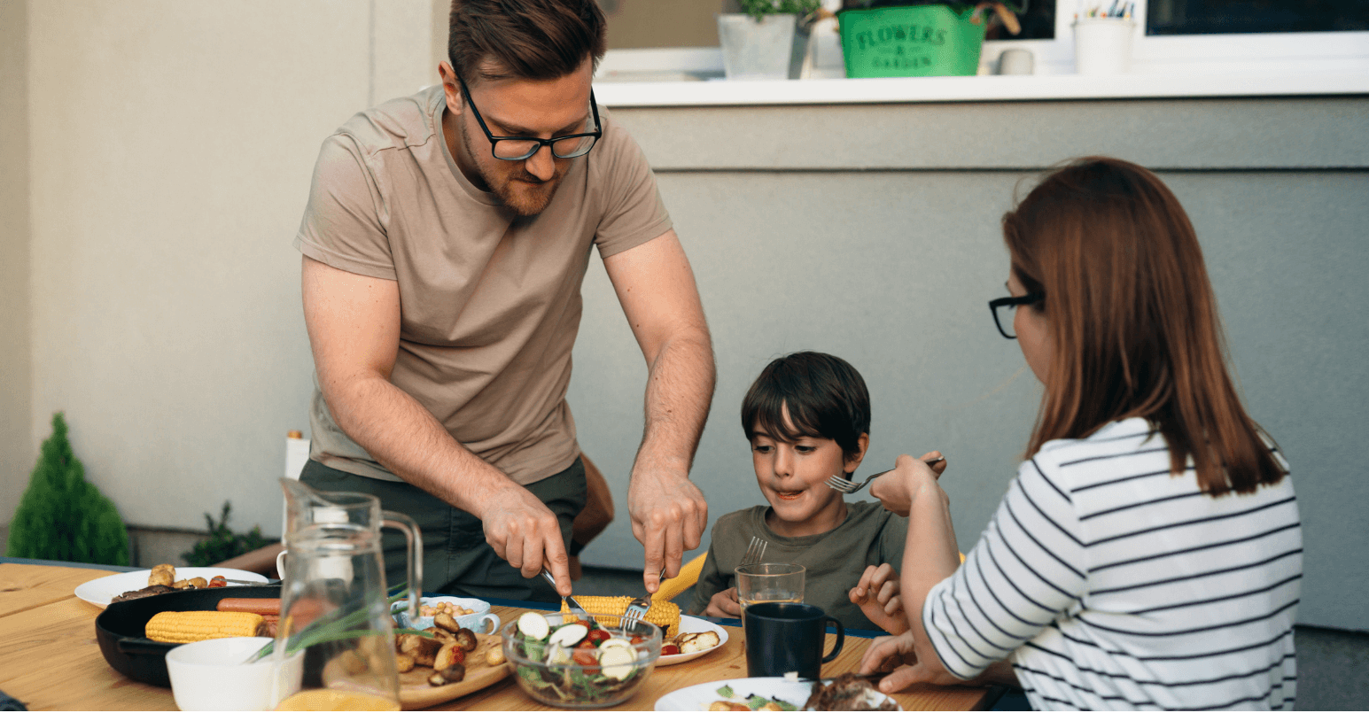 A father cutting up the food on his child's plate