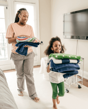 A mother and child carrying folding laundry