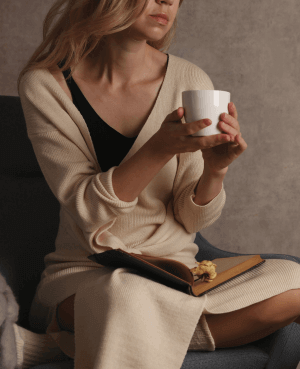 A women sitting cross legged and holding a cup of tea