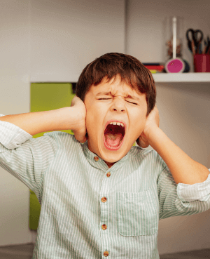 Child screaming with hands over his ears