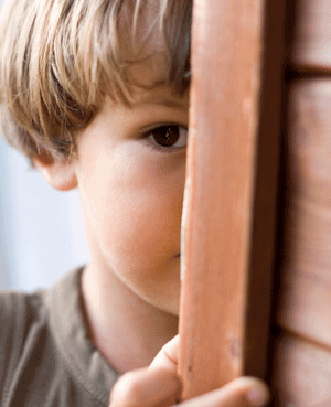 Shy child hiding behind a curtain