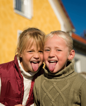 Two childhood friends sticking their tongues out