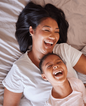 Mom and daughter laying on the bed while laughing