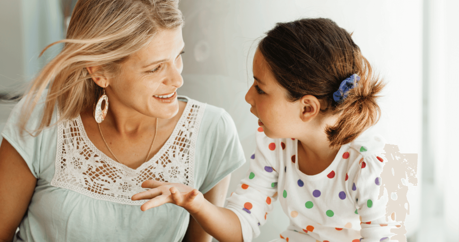 Adult woman listening attentively to a young girl speaking, highlighting active listening and the development of communication skills in children. Perfect for discussions on kids' essential life skills.