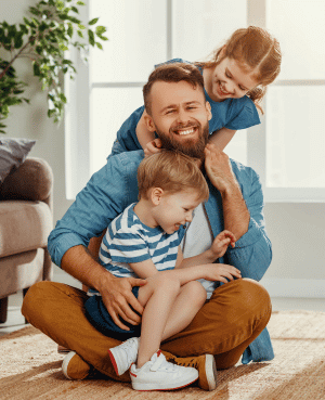 Happy father playing with his two children, symbolizing successful strategies for raising self-driven kids.