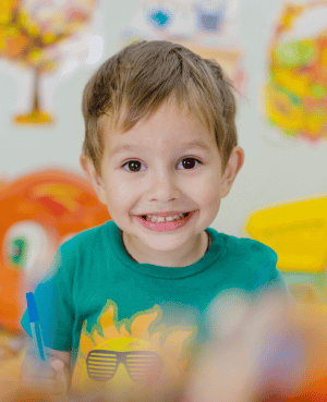 Smiling young boy in a classroom setting, representing positive emotional development.