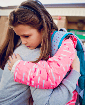 Young schoolgirl hugging an adult for comfort before or after school.
