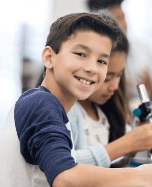 Smiling preteen boy in a classroom learning environment.