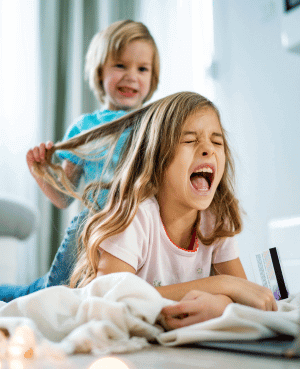 Child pulling another child’s hair while the sibling screams in pain.