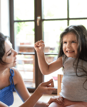 Mother supports young daughter experiencing a meltdown at home.