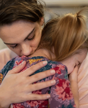 Mother hugging upset child to provide comfort and connection.