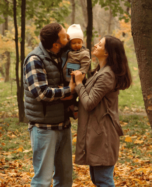 Parents holding their baby in a park, representing family bonding and emotional safety.