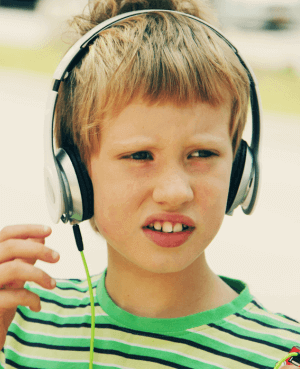 Child listening through silver headphones, practicing sensory regulation.