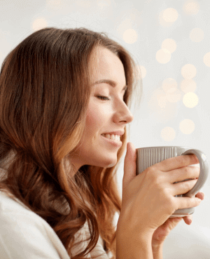 Woman smiling while holding a warm mug, reflecting calm and self care during perimenopause.