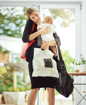 Overwhelmed mom holding a baby and bags, illustrating mom guilt and the mental load.
