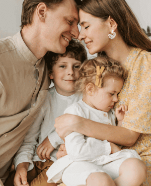 Parents cuddling with two young kids, reflecting connection during the marriage after kids season.