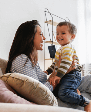 Parent holding a toddler on a couch, showing comfort and co-regulation during clingy phases.
