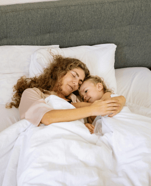 Parent cuddling a child in bed at night, illustrating comfort, co sleeping, and bedtime anxiety support.