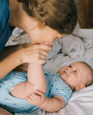 Parent cuddling a baby in bed, showing comfort, safety, and early secure attachment.