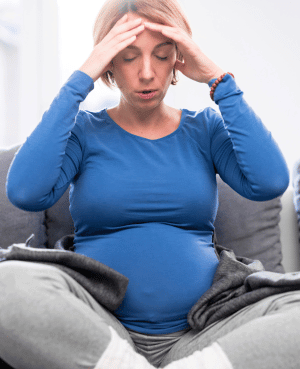 Pregnant woman sitting with her hands on her head, showing overwhelm and anxiety during pregnancy.