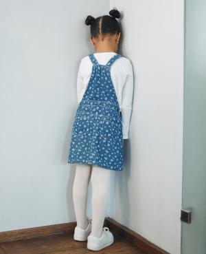 Young child standing in a corner, representing timeout, discipline, and behavior correction.