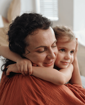 Caregiver holding a child close, representing reassurance, connection, and support around family separation.