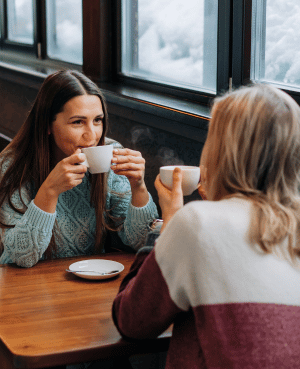 Two women talking over coffee, showing connection, friendship, and feeling valued.
