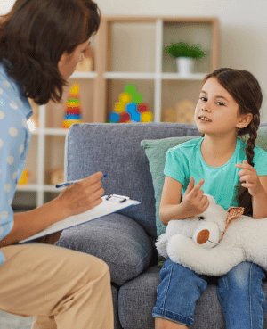 Child talking with therapist while holding a stuffed animal, showing therapy explained with warmth and trust.
