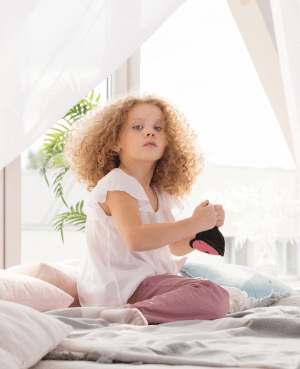 Child sitting on a bed, representing bedtime self-soothing, privacy, and shame-free body boundaries.