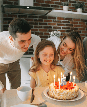 Family gathered around a child’s birthday cake, representing secure attachment across childhood development.