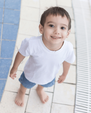 Preschool child smiling near a pool, representing toddler manners and age-appropriate communication.