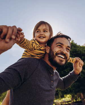 Father carrying child outdoors, representing connection, presence, and secure attachment after trauma.