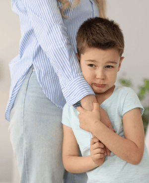 Preschooler holding a parent’s arm, showing anxiety, sensitivity, and a need for reassurance.