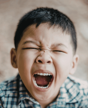 Young boy yelling, representing negative self-talk, intense frustration, and big emotions in children.