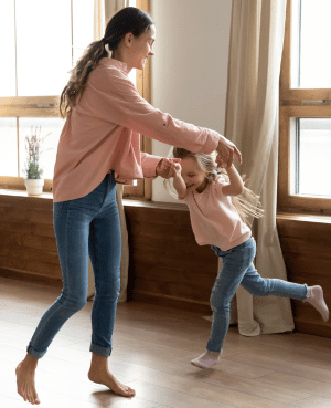 Mother and young child dancing together at home, showing music, play, and connection that support secure attachment.