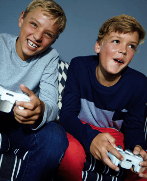 Two boys enjoying video games side by side, showing how shared activities can create opportunities for connection.