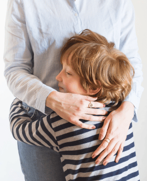 Young child hugging a caregiver, illustrating comfort, co-regulation, and support after stressful moments.